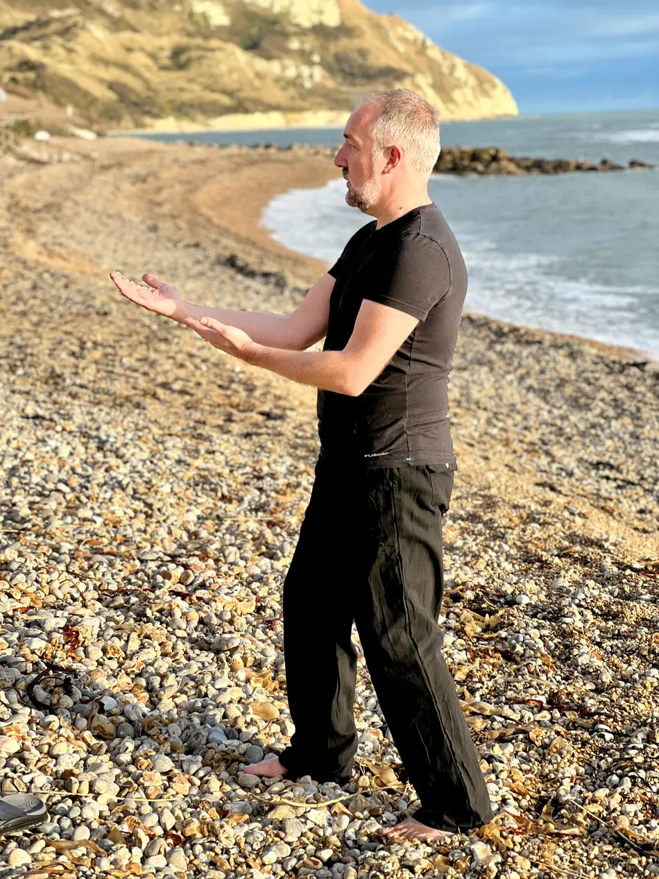 Andrew Lowe performing tai chi on a beach
